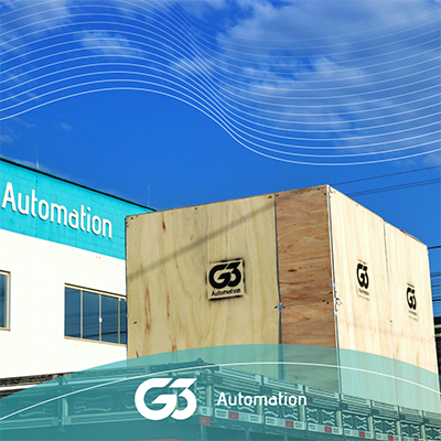 Robô G3 Automation encaixotado sobre caçamba aberta de caminhão com fachada atrás em perspectiva.